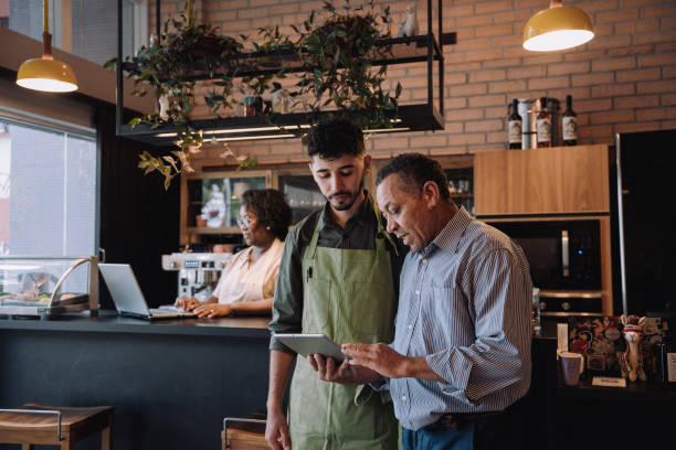 Horecaondernemer bespreekt teamontwikkeling met medewerker op de werkvloer van een koffiezaak
